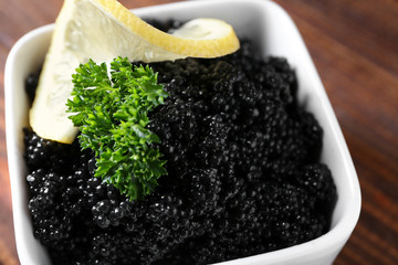 Bowl with delicious black caviar on table, closeup