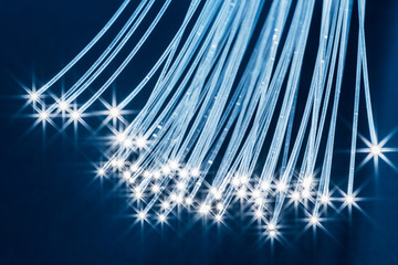 Bundle of optical fibers with lights in the ends. Blue background.