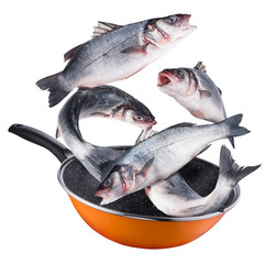 Flying seabass fishes falling into a frying pan. Clipping path.