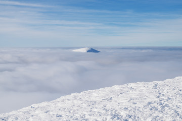 Fototapeta na wymiar Fresh sparkling snow cover on mountain tops. Cloudy sky at the background.