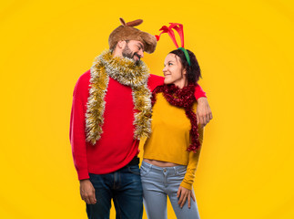 Happy couple dressed up for the christmas holidays on yellow background