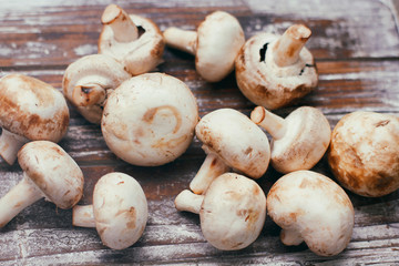 Fresh raw champignon mushrooms on wooden table. Cooking process. Modern kitchen.