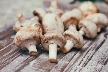 Fresh raw champignon mushrooms on wooden table. Cooking process. Modern kitchen.