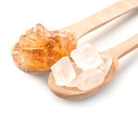 Wooden spoons with different sugar on white background
