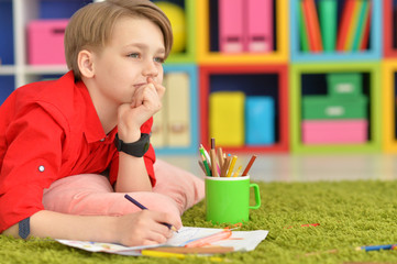 Portrait of cute little boy drawing at home
