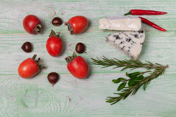 Breakfast with blue cheese and persimmons, chestnuts on wooden background