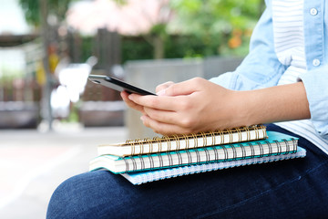 Student girl holding books and using smartphone, online education, technology communication