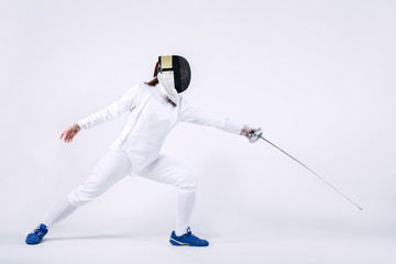 Young fencer athlete wearing mask and white fencing costume. holding the sword. Isolated on white...