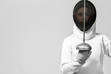 Young fencer athlete wearing fencing costume holding the sword and mask. Isolated on white background - obrazy, fototapety, plakaty