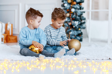 Twin brothers in front of the christmas tree  with candles and gifts. New year's eve. Cozy holiday at the fir-tree. love, happiness and big family concept