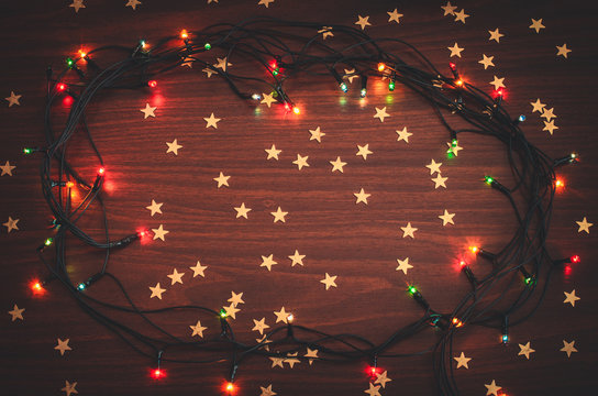 Beautiful Christmas Glowing Garland With Golden Star Confetti On The Wooden Table Top View Toned Background Copy Space