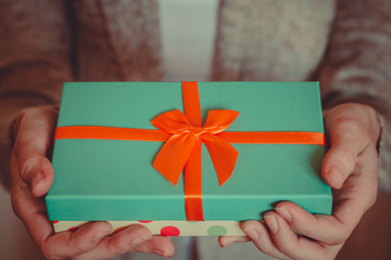 Young woman holds a gift box with a bow close up