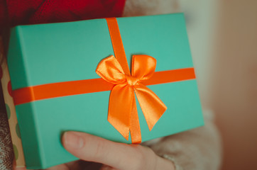 Young woman holds a bright gift box with a bow close up