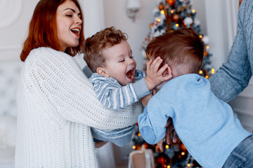 A family of four hugging in front of the christmas tree. New year's eve. Cozy holiday at the fir-tree. love, happiness and big family concept