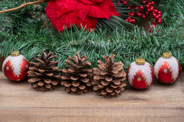 Winter holiday decoration: Blooming Red Poinsettia, Pine, Berry bush, Christmas tree balls, pine cone on wooden background.