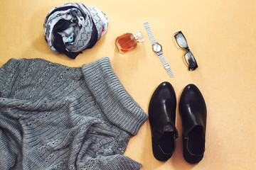 Set of women's autumn, winter clothes:   gray pullover oversize, black boots and scarf, glass perfume bottle, silver hand watch, eyeglasses. Fashionable clothes for walks, flat lay