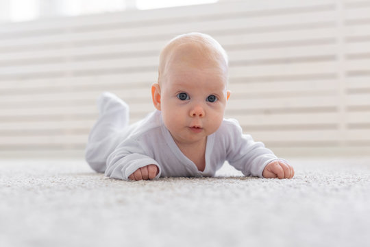 Childhood, infant and people concept - small baby lying on the floor