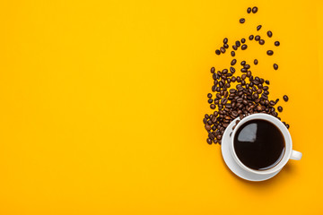 Spilled coffee beans on a bright yellow background