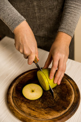 Woman cuts green apple on board close