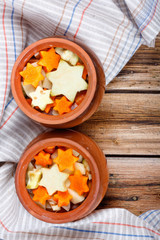 Traditional rustic home vegetable stew in two clay pots on old vintage wooden table.