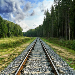 Fototapeta premium Summer railway view with forest and cloudy sky in Russia