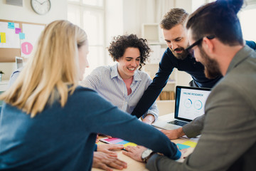 Group of young businesspeople with laptop working together in a modern office.