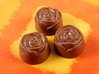 THREE CHOCOLATE FLOWERS ON ORANGE