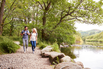 Couple Hiking Along Path By River In UK Lake District