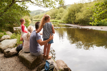 Family On Hike Looking Out Over River In UK Lake District