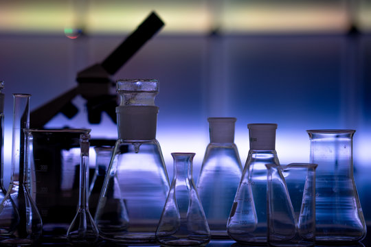Empty chemical glassware on color background. Group of laboratory empty flasks   on color scientific background reflection on a table