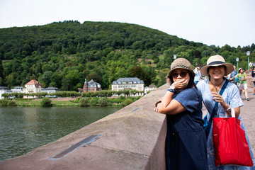 Asian thai women mother and daughter travel and posing for take photo on Karl Theodor Old Bridge at Heidelberg, Germany