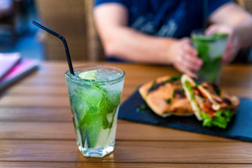 Mojito cocktail with lime and mint in glass on wooden table