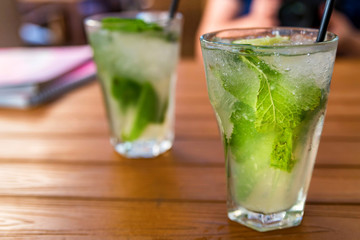 Two glasses of mojito cocktail with lime and mint on wooden table