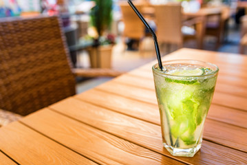 Mojito cocktail with lime on wooden table with blurred restaurant background