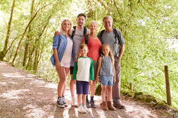 Portrait Of Multi Generation Family Enjoying Walk Along Woodland Path Together