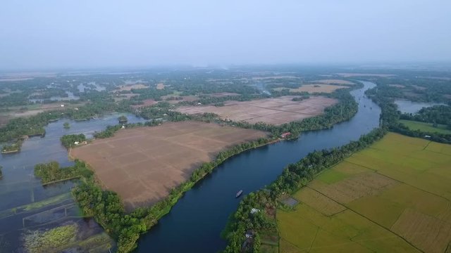 A tilting, aerial, dolly, long shot of the magnificent graphic pattern of the terrain, including the houses and the trees on the shore.