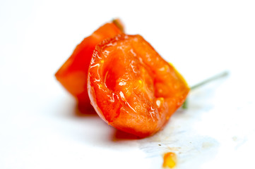 halves of a cherry tomato with juice drops on a white