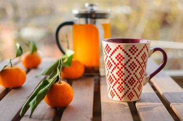 Glass teapot, mug and tangerines on wooden table