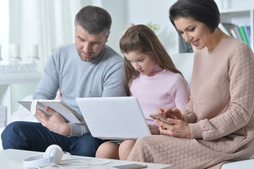 Happy parents and daughter using digital devices