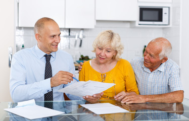 Aged couple signing financial agreement with bank worker