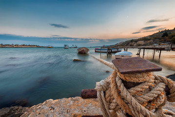 Amazing long exposure landscape at rope anchoring fishing boat at the pier.