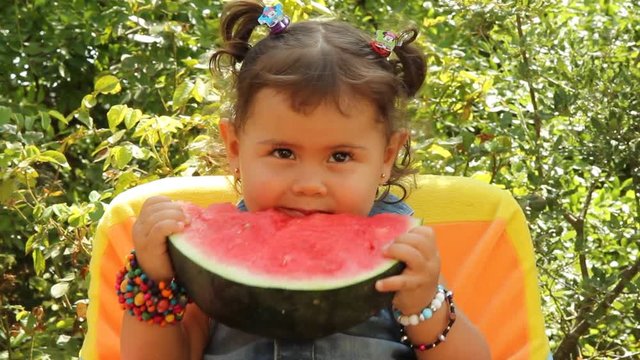 Little girl eating a watermelon.