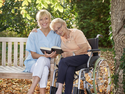 Carer reads a book to the elderly person