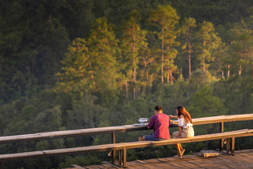 Back view of man embracing his beautiful woman while having romantic picnic mountains.