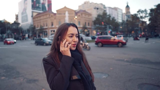 Young businesswoman walking through the square and speaking on the phone.