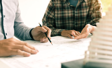 Two architect people sitting and presents plan on blueprints.