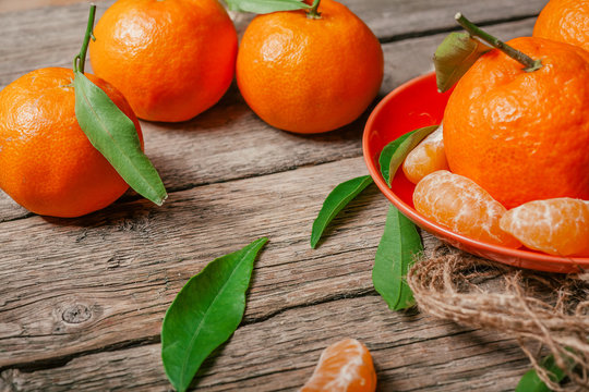 Tangerines with leaves and cinnamon stick on old wooden table.
