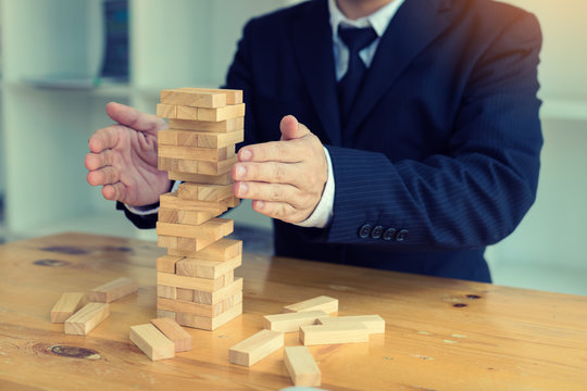 Hands of businessman protect block wooden on table with risk concept.