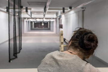 Frau mit Dutt visiert Zielscheibe mit Gewehr an 2