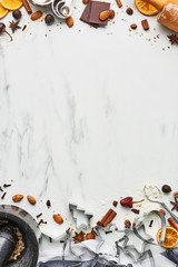 Holiday baking background for baking Christmas cookies with cutters, rolling pin, mortar, chocolate and spices on white marble table with copy space for text. Top view.